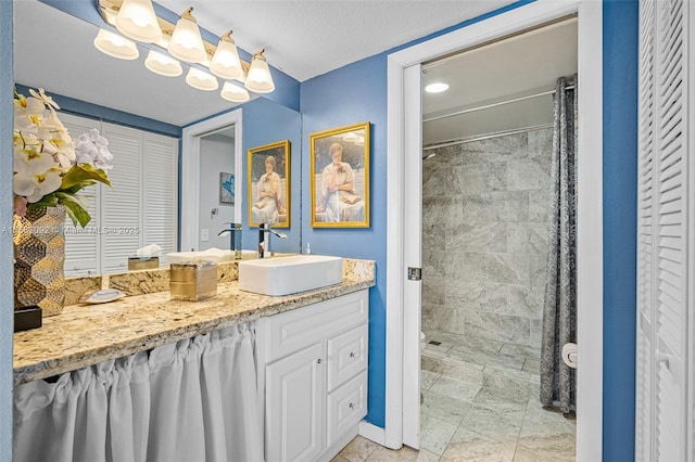 bathroom with a textured ceiling, vanity, and walk in shower