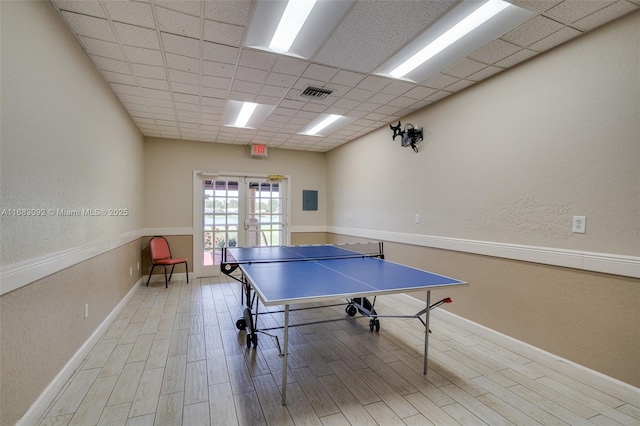 recreation room featuring french doors, a paneled ceiling, and wood-type flooring