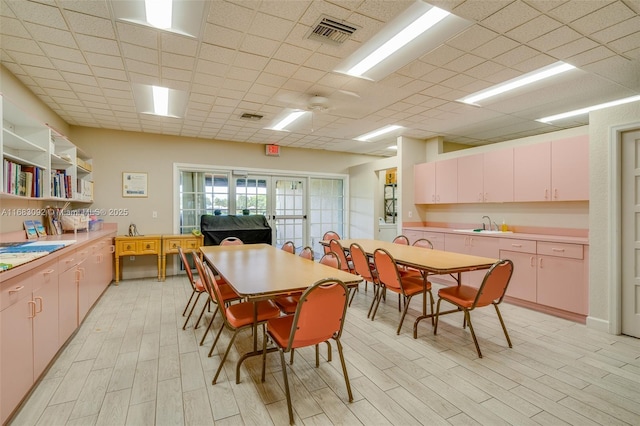 dining space featuring french doors, a paneled ceiling, light hardwood / wood-style flooring, and sink