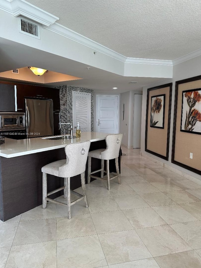 kitchen with crown molding, a textured ceiling, stainless steel appliances, and sink