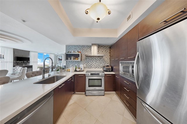 kitchen with dark brown cabinetry, sink, appliances with stainless steel finishes, and wall chimney range hood