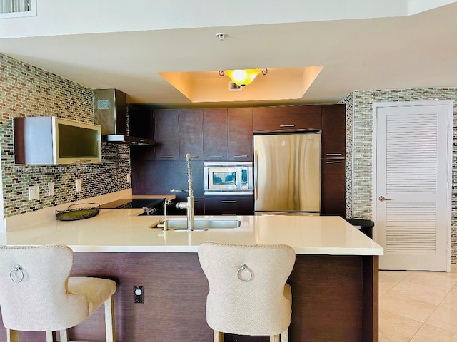 kitchen featuring appliances with stainless steel finishes, kitchen peninsula, a kitchen bar, and a raised ceiling