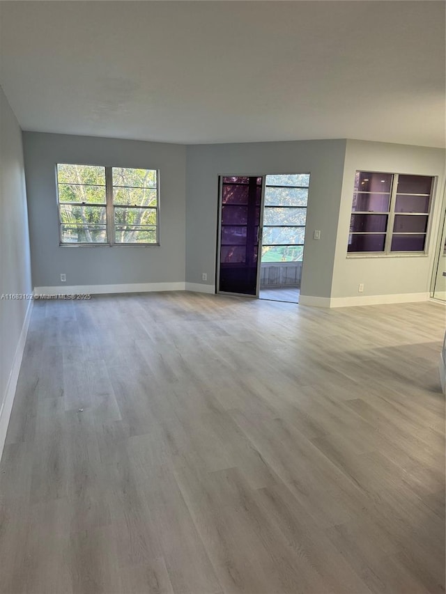 12800 SW 7th Ct Unit 313G, Pembroke Pines, FL 33027 - unfurnished living room featuring wood finished floors, baseboards, and healthy amount of natural light