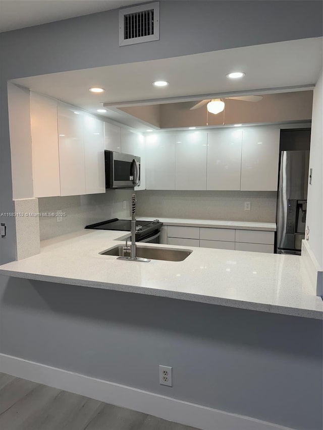 12800 SW 7th Ct Unit 313G, Pembroke Pines, FL 33027 - kitchen featuring stainless steel appliances, a peninsula, white cabinets, decorative backsplash, and recessed lighting