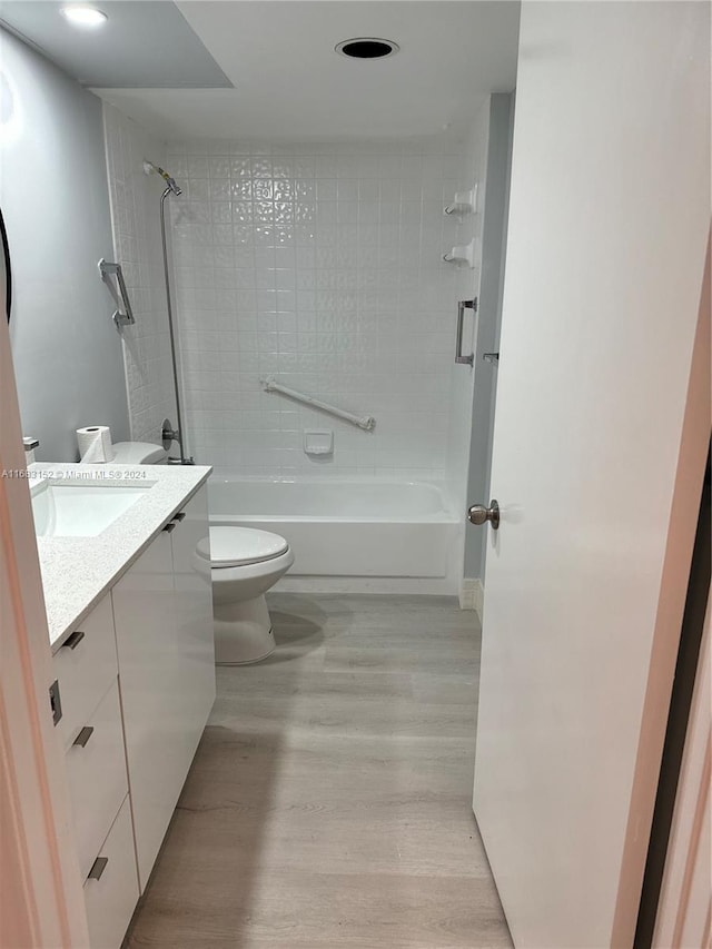 full bathroom featuring hardwood / wood-style floors, vanity, toilet, and tiled shower / bath combo