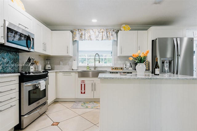 kitchen featuring tasteful backsplash, appliances with stainless steel finishes, light tile patterned flooring, sink, and white cabinetry