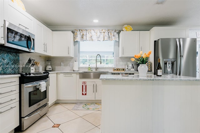 2610 SW 16th St, Fort Lauderdale, FL 33312 - kitchen featuring decorative backsplash, light tile patterned flooring, white cabinets, a sink, and stainless steel appliances