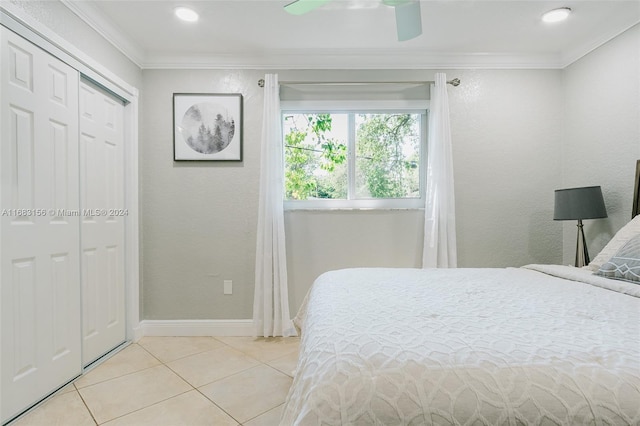 tiled bedroom with a closet, ceiling fan, and crown molding