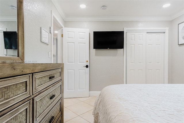 bedroom featuring a closet, crown molding, and light tile patterned flooring