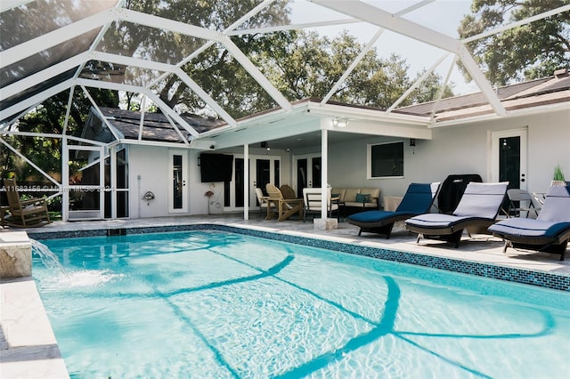 view of pool with a patio, ceiling fan, pool water feature, and glass enclosure