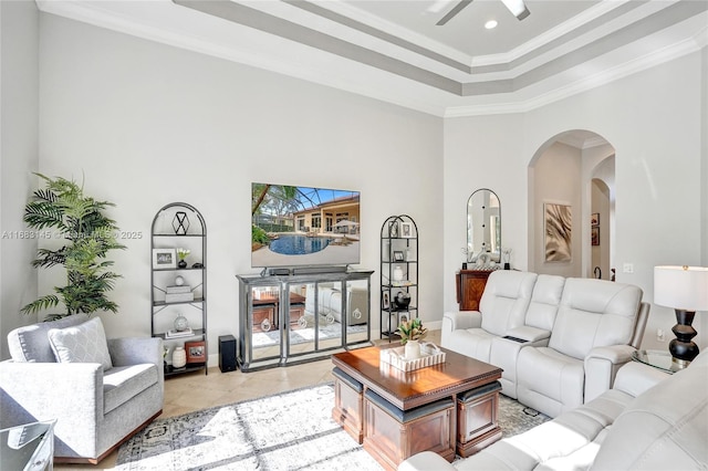 tiled living room featuring crown molding, a tray ceiling, and a high ceiling