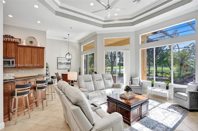 living room featuring crown molding, light tile patterned floors, a raised ceiling, a towering ceiling, and ceiling fan with notable chandelier