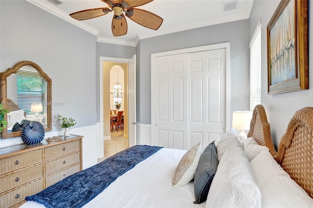 bedroom with ornamental molding, light tile patterned floors, ceiling fan, and a closet