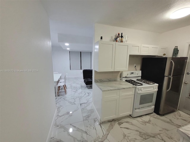 kitchen featuring stainless steel fridge, white cabinets, light stone countertops, and white gas range oven