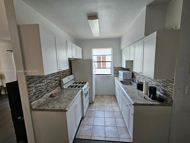 kitchen featuring white cabinets, tasteful backsplash, stone counters, sink, and white appliances