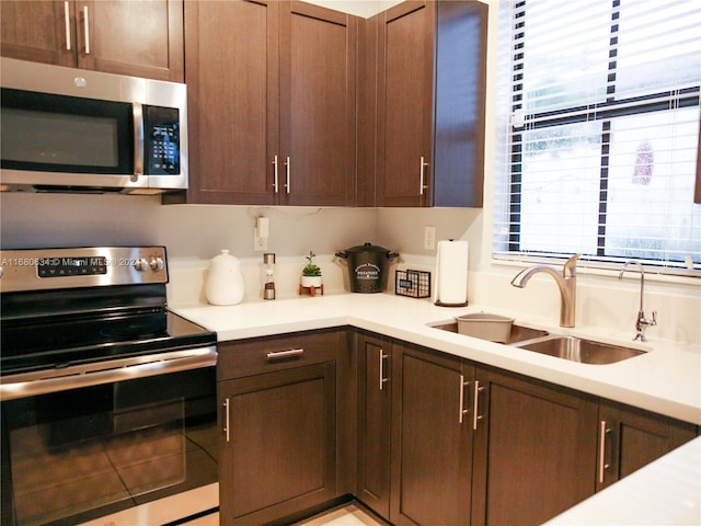 kitchen with stainless steel appliances, dark brown cabinetry, and sink