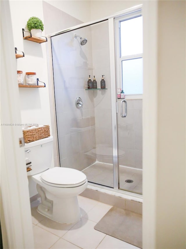 bathroom featuring a shower with door, tile patterned floors, and toilet