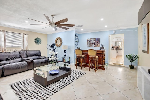 living room with ornamental molding, ceiling fan, indoor bar, and light tile patterned floors