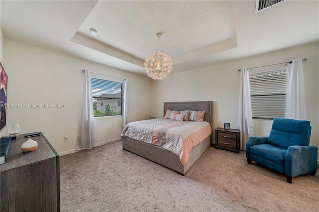 bedroom featuring a chandelier, light colored carpet, and a raised ceiling