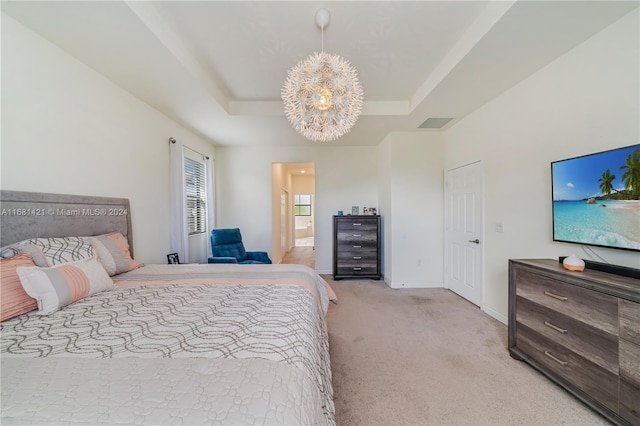 bedroom with connected bathroom, light carpet, a tray ceiling, and an inviting chandelier