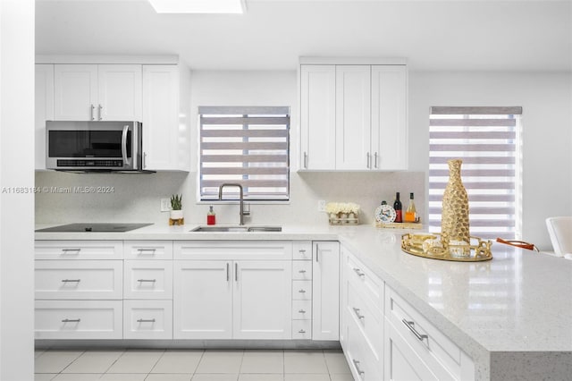 kitchen featuring white cabinets, sink, light stone counters, and black electric cooktop