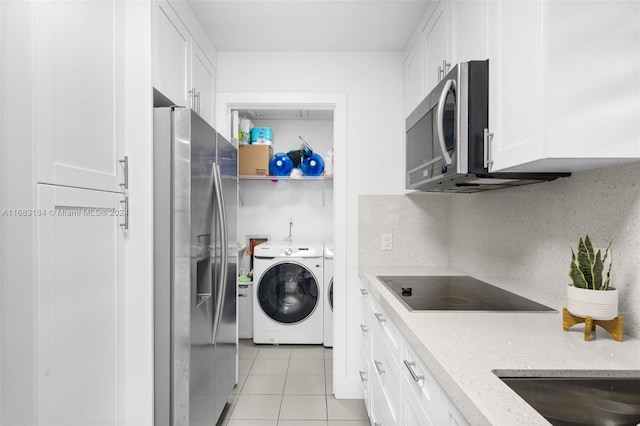 kitchen with stainless steel appliances, light tile patterned floors, washer / clothes dryer, light stone countertops, and white cabinets