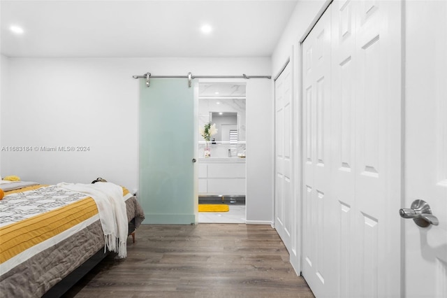 bedroom with dark hardwood / wood-style flooring, a barn door, and a closet