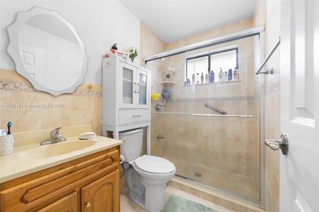 bathroom with tile patterned floors, toilet, tile walls, vanity, and walk in shower