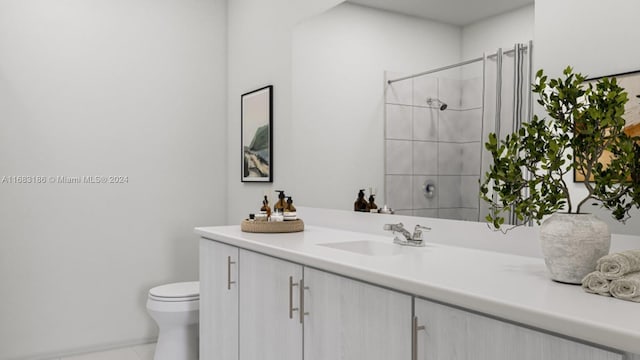 bathroom with vanity, toilet, and a tile shower