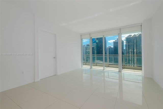 empty room with a wall of windows and light tile patterned floors