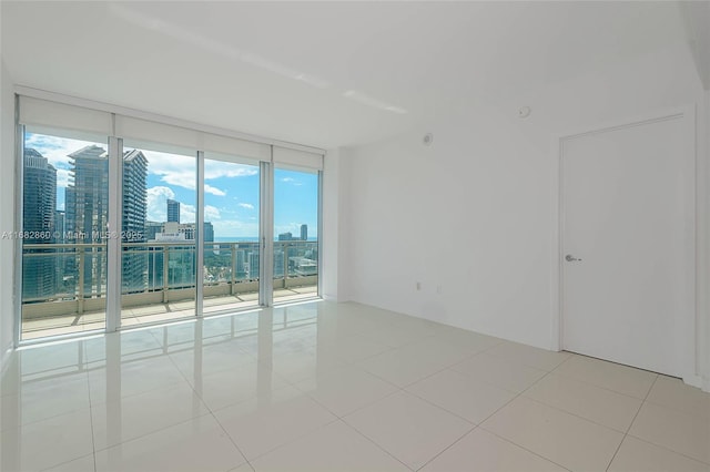 spare room featuring floor to ceiling windows and light tile patterned floors