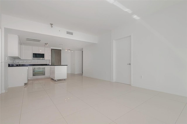 kitchen with light tile patterned flooring, white cabinets, and oven