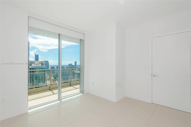 unfurnished room with a wall of windows and light tile patterned floors