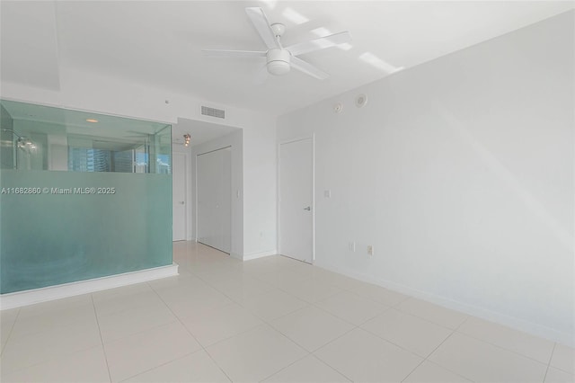 empty room with ceiling fan and light tile patterned floors