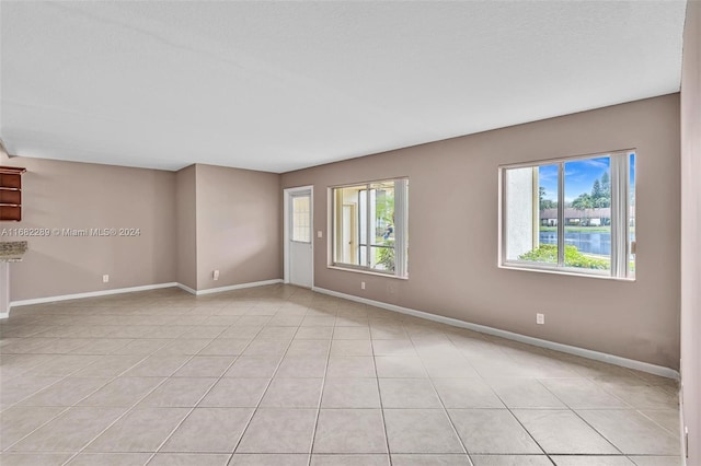 tiled empty room with a wealth of natural light and a water view