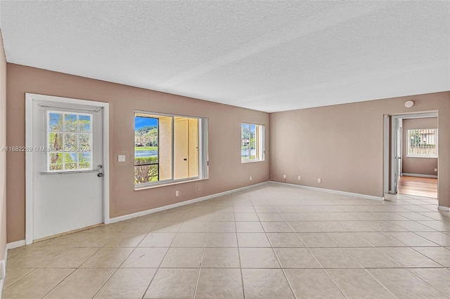 empty room with light tile patterned floors and a textured ceiling