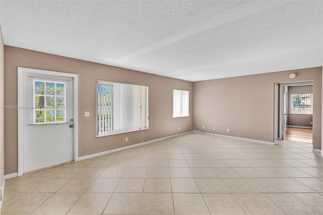 spare room with light tile patterned flooring and a textured ceiling