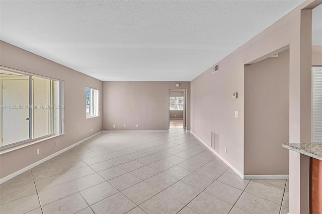 tiled spare room with plenty of natural light and a textured ceiling