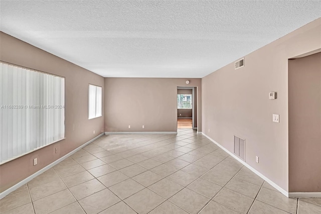 empty room with light tile patterned flooring and a textured ceiling