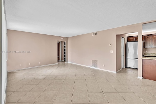 tiled spare room with a textured ceiling