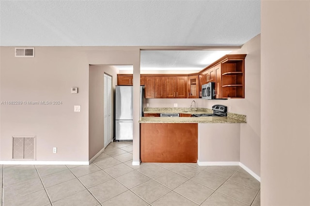 kitchen with kitchen peninsula, appliances with stainless steel finishes, a textured ceiling, and light tile patterned floors