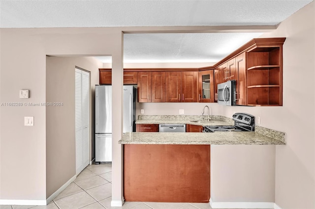 kitchen featuring sink, a textured ceiling, appliances with stainless steel finishes, light stone counters, and kitchen peninsula