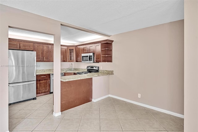 kitchen with sink, light tile patterned flooring, stainless steel appliances, and a textured ceiling