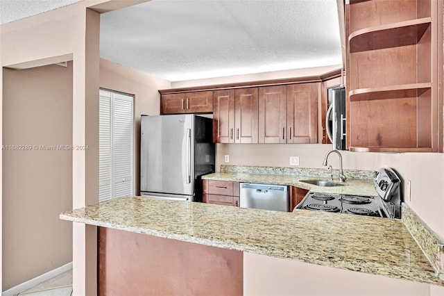 kitchen featuring light stone countertops, sink, stainless steel appliances, kitchen peninsula, and a textured ceiling