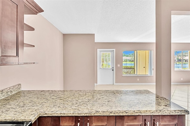 kitchen featuring light stone counters, light tile patterned floors, and a textured ceiling