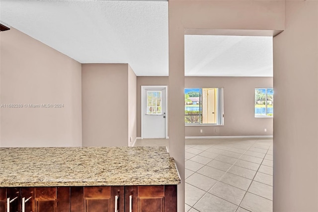 kitchen featuring light tile patterned flooring, light stone countertops, and a textured ceiling