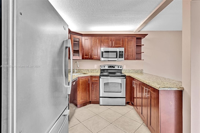 kitchen featuring light stone countertops, sink, stainless steel appliances, a textured ceiling, and light tile patterned floors