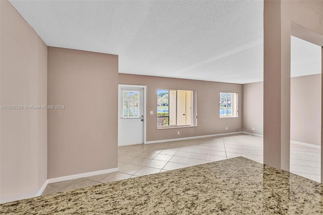 tiled empty room featuring a textured ceiling