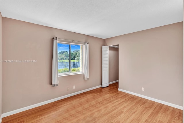 spare room featuring light hardwood / wood-style flooring and a textured ceiling