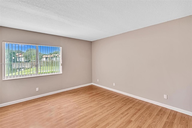 empty room with light hardwood / wood-style flooring and a textured ceiling